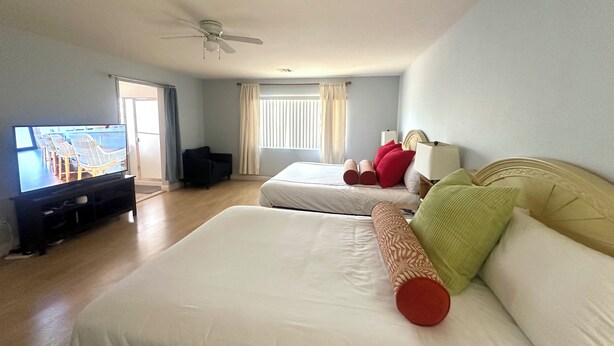 A hotel room with two beds, a ceiling fan, a TV, and a window with curtains. - County Licensed STR! Comfortable, spacious home 15 minutes to The Strip (Las Vegas)