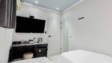 Quarto de hotel com escrivaninha, televisão de tela plana, cafeteira e minibar.