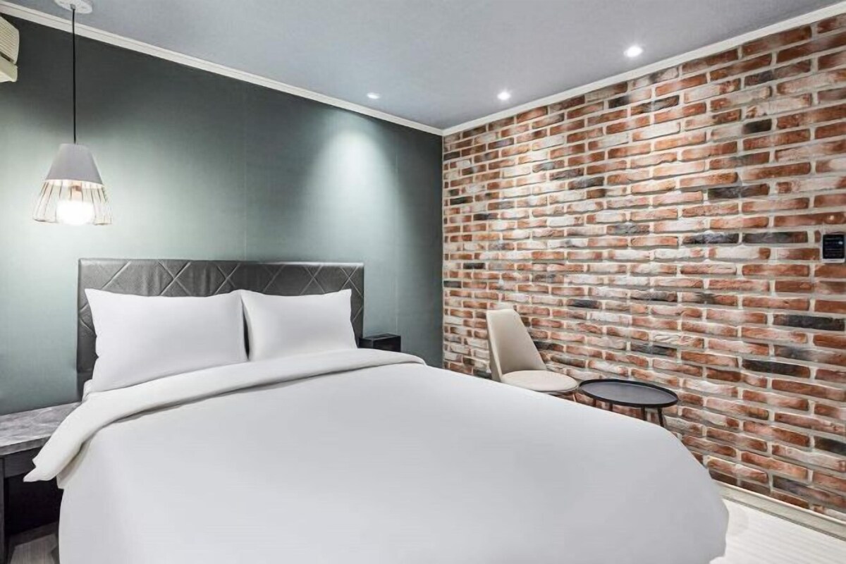 Une chambre d’hôtel avec un lit, une table de chevet, une chaise et une petite table.