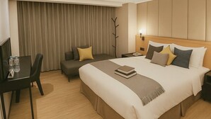 Une chambre d’hôtel avec un grand lit, un bureau avec une chaise, un canapé et une télévision.