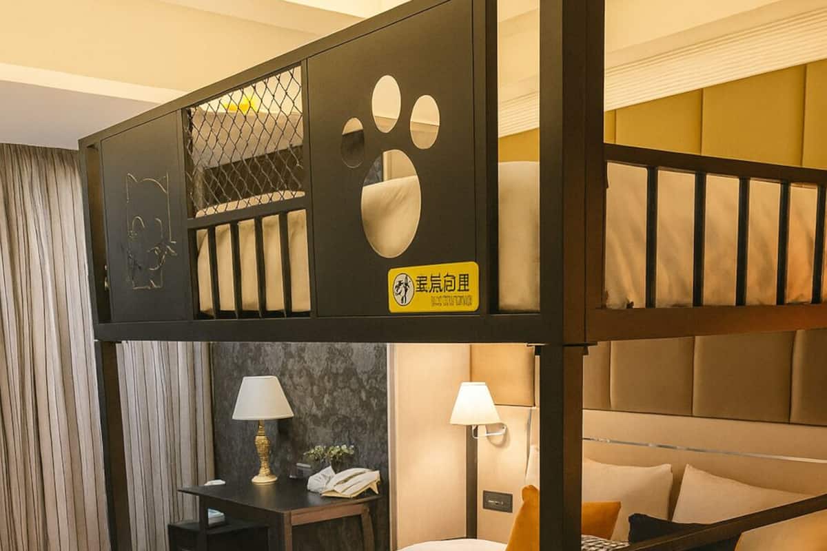 Une chambre avec un lit superposé, un bureau, une lampe et un coussin à carreaux.