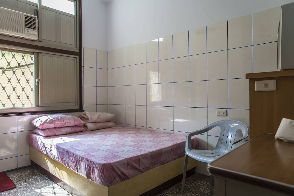 A small, clean room with a bed, a chair, and a desk.