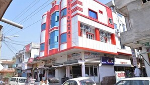 A multi-story hotel with a red and white facade, multiple air conditioning units, and various signs in a local language. - Hotel Swarat (Satna)