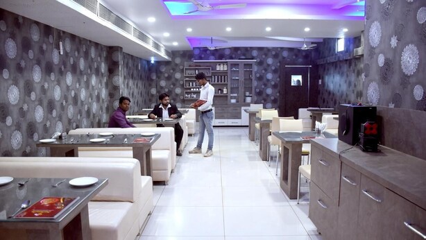 A modern restaurant with white booths, a counter, and a ceiling fan. - Hotel Swarat (Satna)
