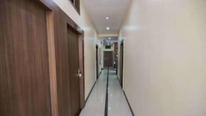 A hallway with wooden doors on the left and a tiled floor. - Hotel Swarat (Satna)