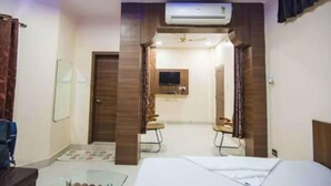 A hotel room with a bed, a desk, an air conditioner, a television, and a mirror. - Hotel Swarat (Satna)