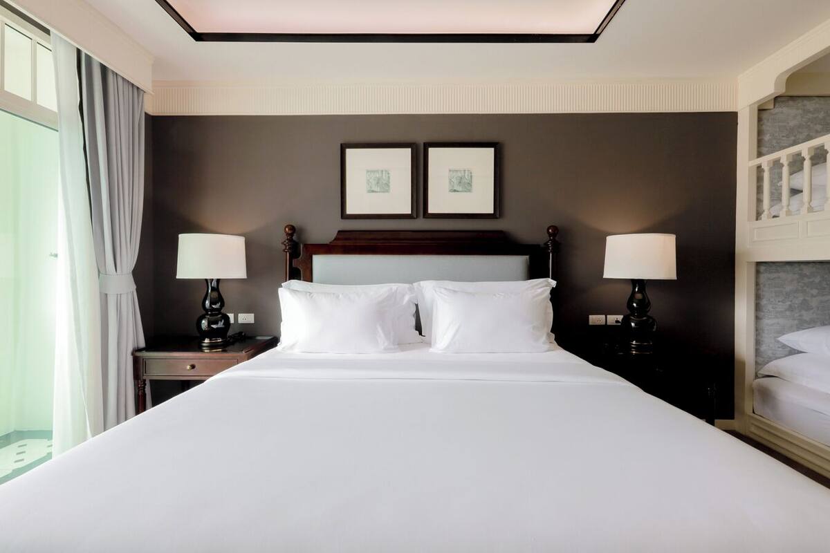 Habitación de hotel con una cama grande, dos mesitas de noche con lámparas, un cabecero y dos cuadros enmarcados en la pared.