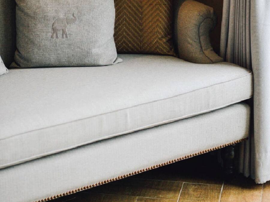 Un sofá con dos almohadas, una cortina y un piso de baldosas.