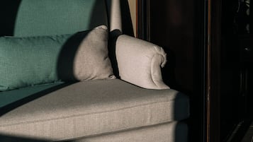 Un sofá con un respaldo alto y reposabrazos, colocado frente a una pared con diseño decorativo.
