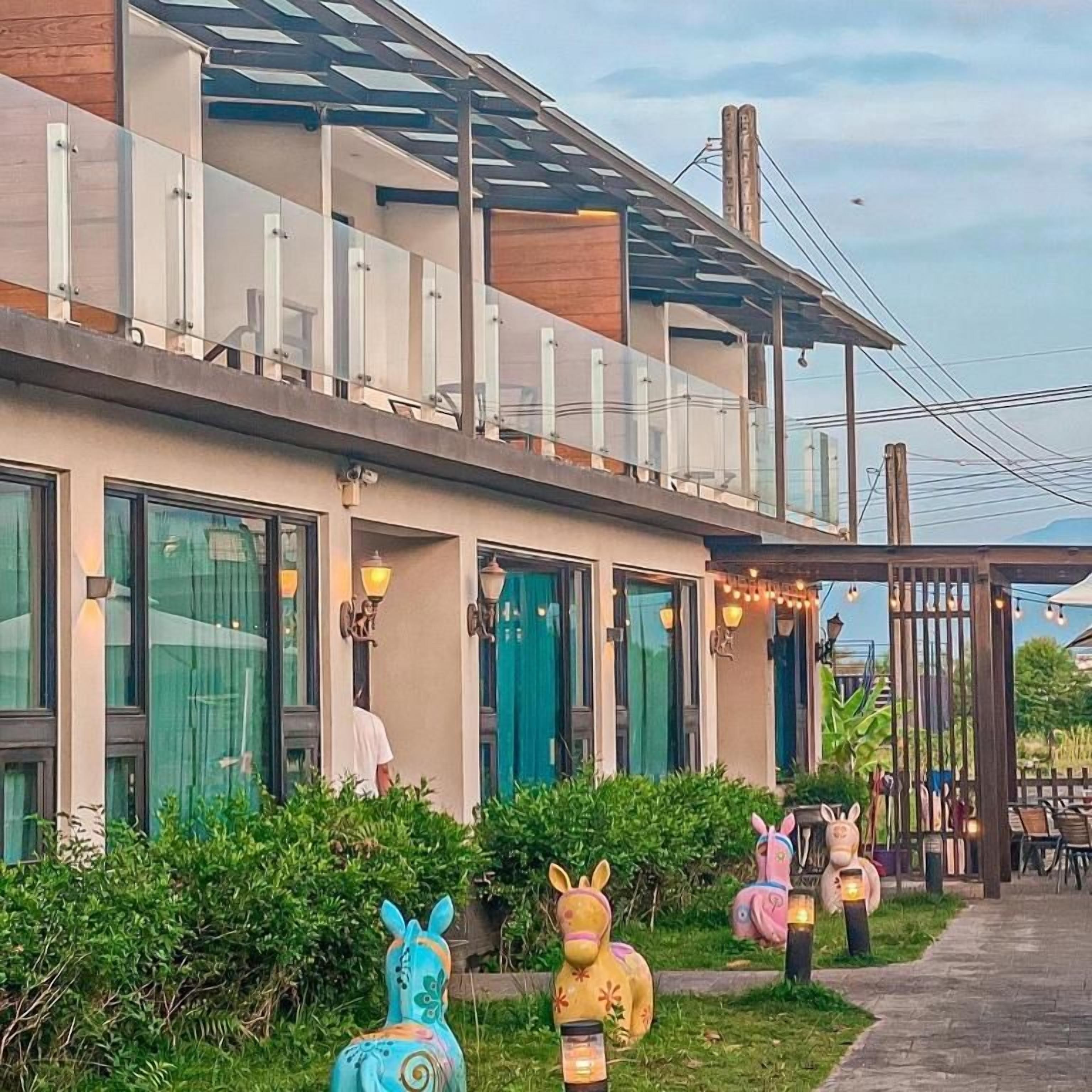 A modern building with a balcony, large windows, and outdoor seating area with decorative animal statues.