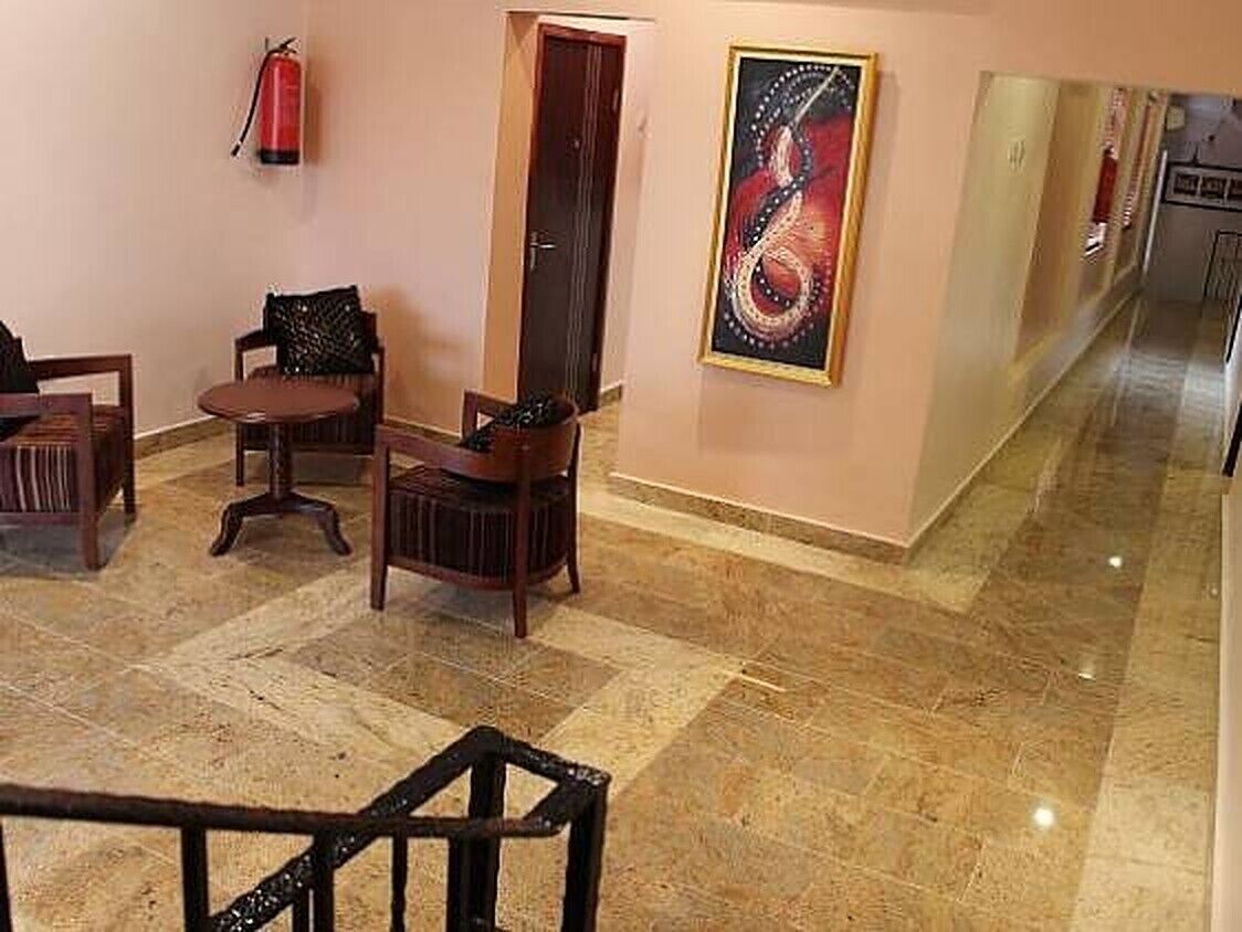 Un vestíbulo con suelo de mármol, muebles de madera, un extintor y una obra de arte enmarcada en la pared.