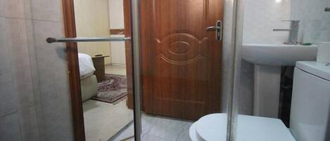 Un baño con inodoro, lavamanos y zona de ducha.