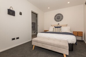 A bedroom with a bed, bedside tables, a wall-mounted artwork, and a bench. - Tree Walk - Redwoods, Spa Pool, Sleeps 10 (Rotorua)
