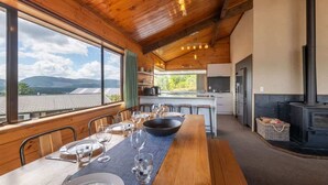 Un intérieur en bois comprenant une table à manger pour quatre personnes, un coin cuisine et une cheminée.
