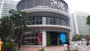Een modern gebouw met een gebogen gevel en grote ramen, met de tekst 'PARIS BEACH CLUB'.