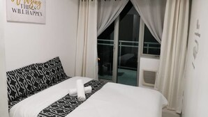 Een hotelkamer met een bed, een raam met gordijnen en een motiverende quote op de muur.