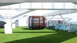 Een moderne architecturale constructie met een opvallend, bolvormig element, omringd door een weelderig groen gazon en witte structurele details.