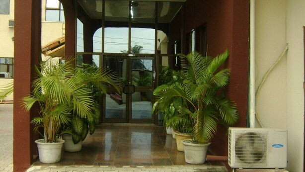 A building entrance with glass doors, potted plants, and an air conditioning unit. - Global Dreams Hotel (Calabar)