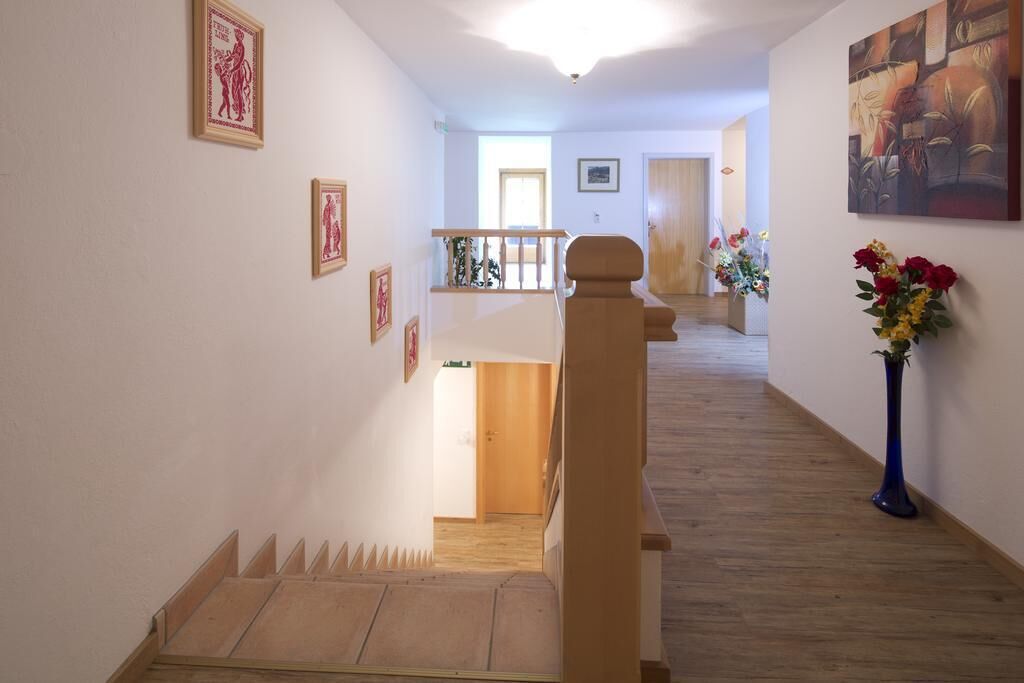 Un escalier avec des marches en bois et une rampe, menant à un palier doté d’une porte et d’un petit balcon.