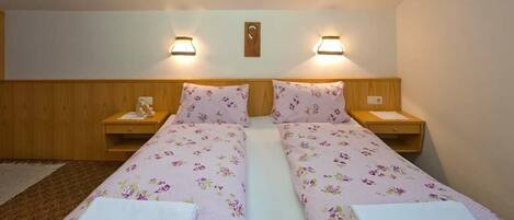Habitación doble con dos camas, cada una con ropa de cama estampada y lámparas de noche.