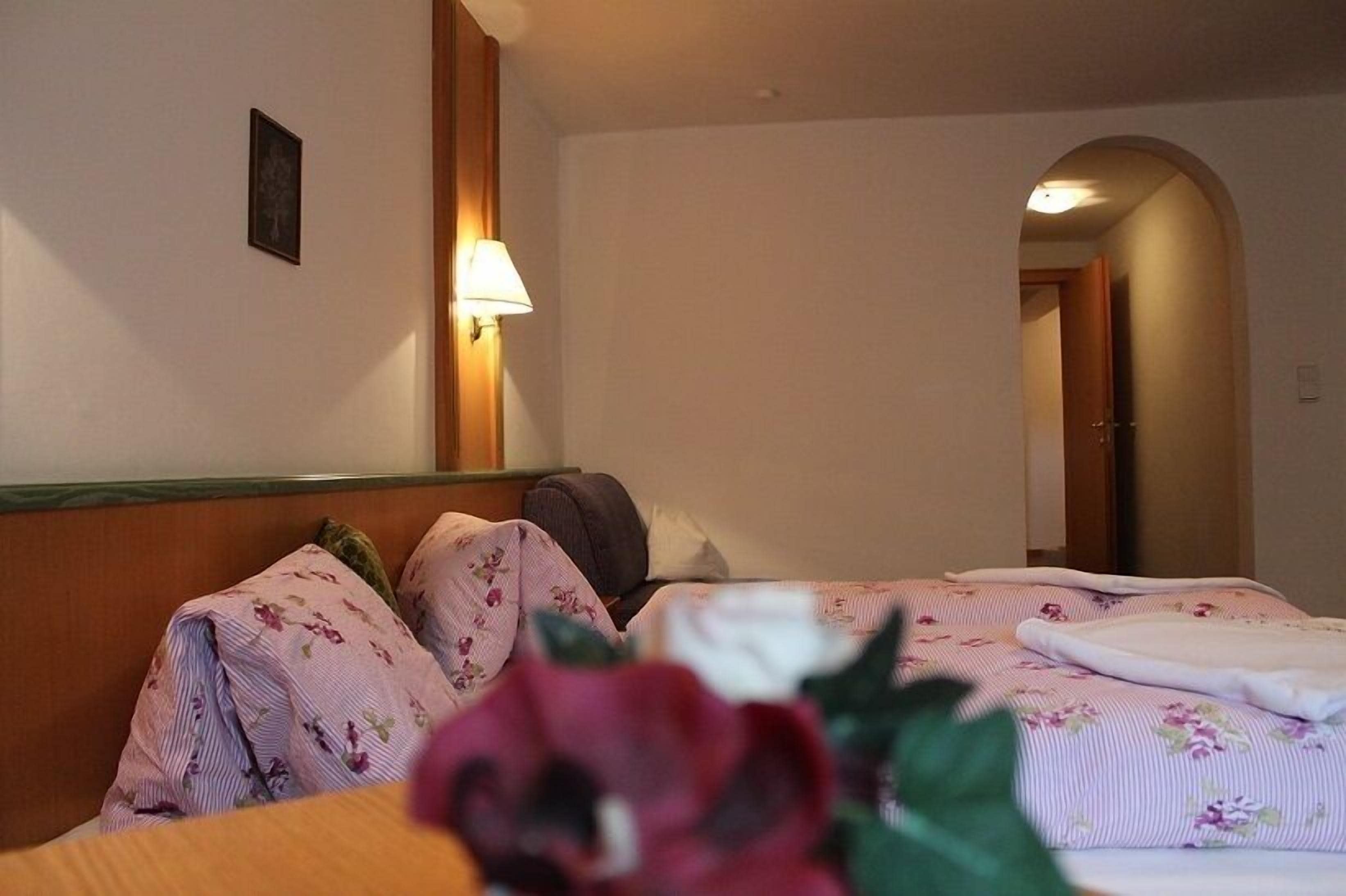 Habitación de hotel con dos camas, una mesita de noche, una lámpara y un cuadro en la pared.