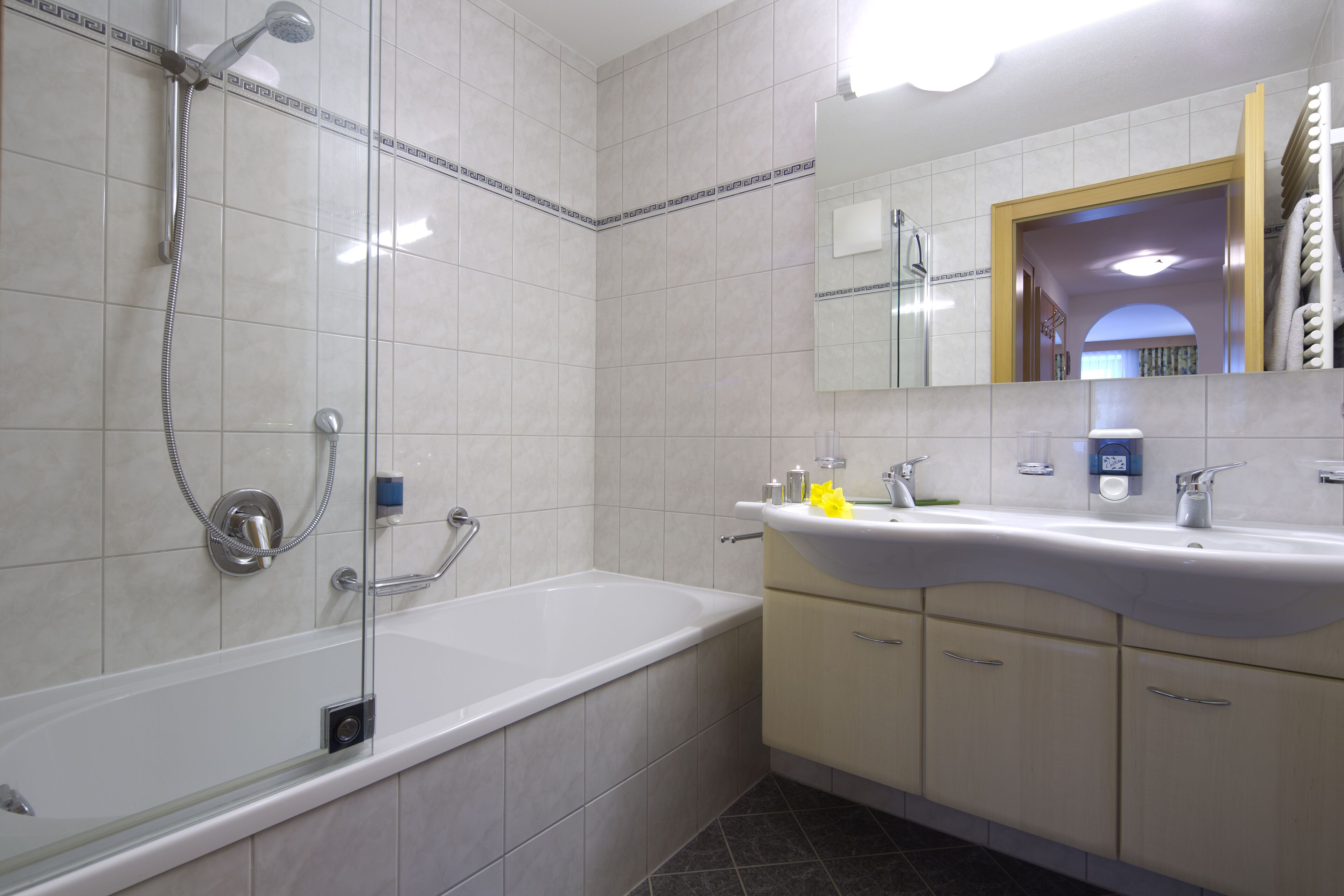 A modern bathroom with a bathtub, shower, and sink.