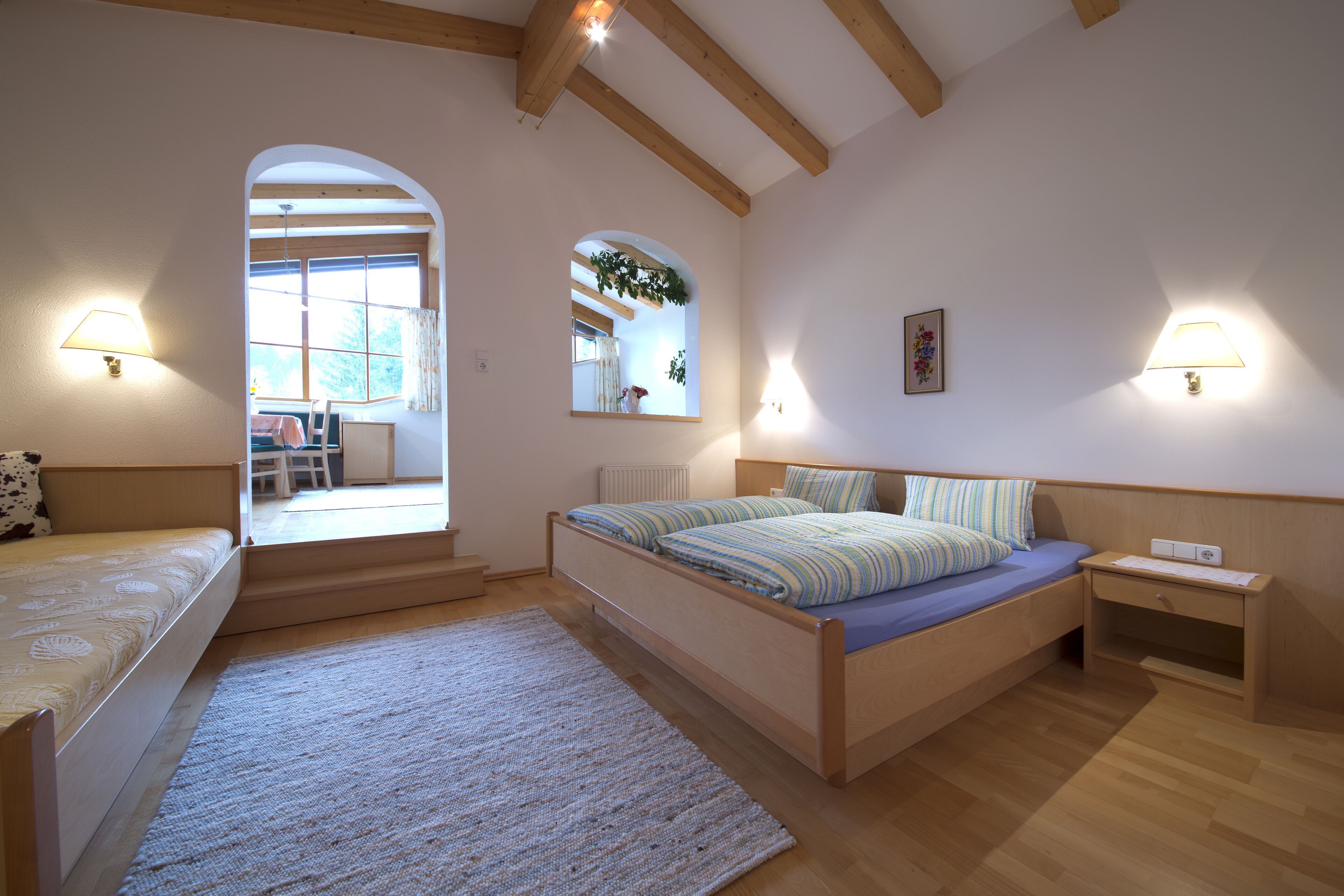 Un dormitorio con una cama, una mesita de noche, una lámpara y una ventana.