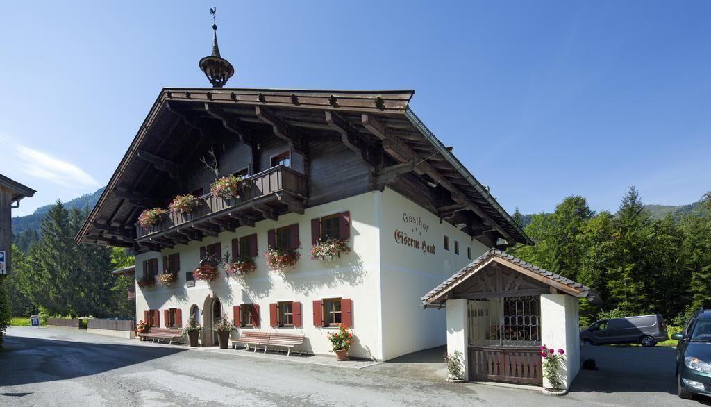 Un bâtiment de style alpin traditionnel, doté d’un toit en pente, de balcons ornés de jardinières et d’une enseigne indiquant  « Gasthof Gasthof ».