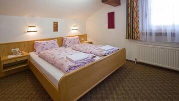 Un dormitorio con una cama de madera, dos mesitas de noche y un ventanal con cortinas.