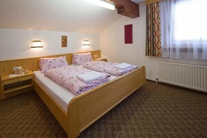 Un dormitorio con una cama de madera, dos mesitas de noche y un ventanal con cortinas.
