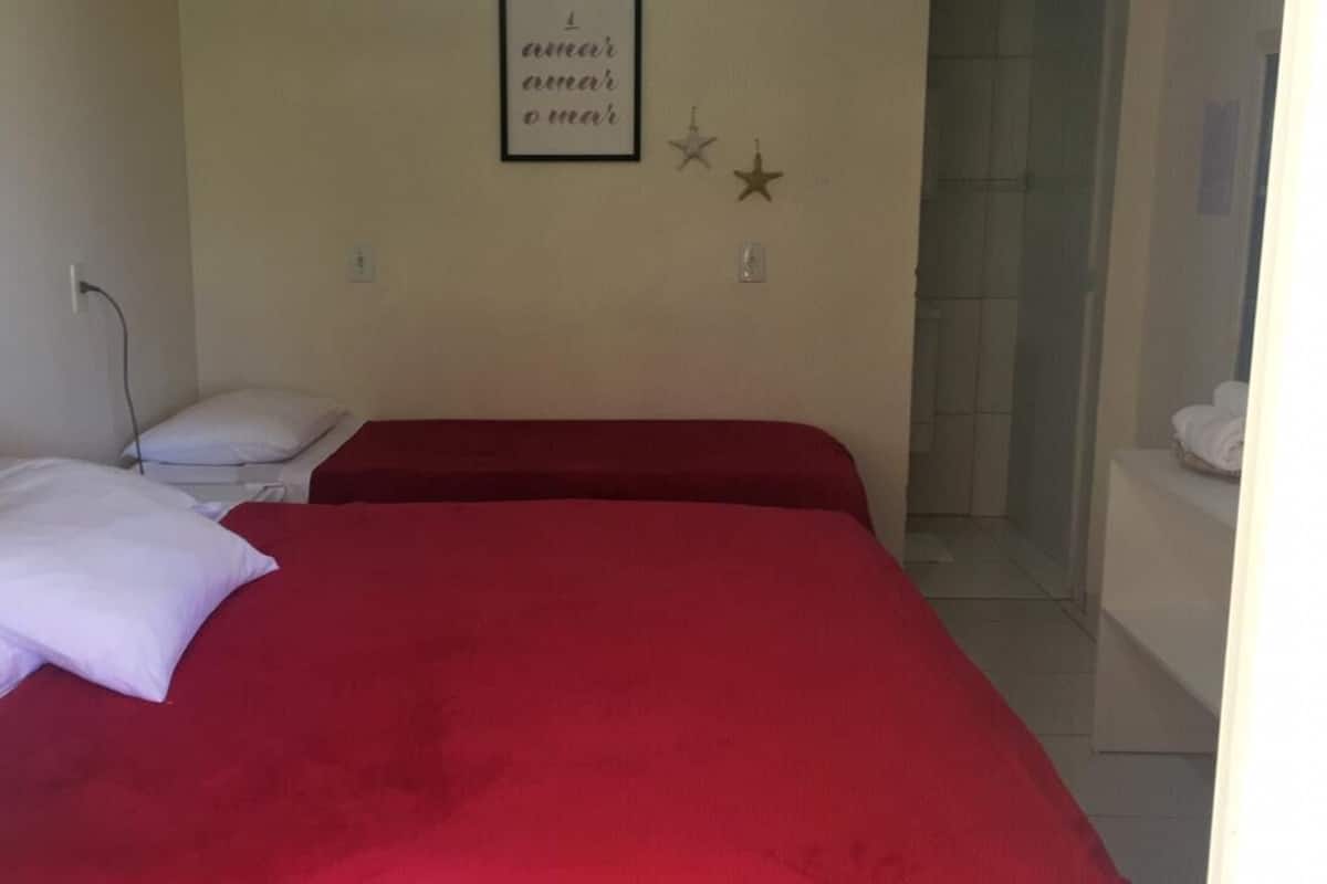 A room with two beds, a wall with a framed quote, and a shower area.