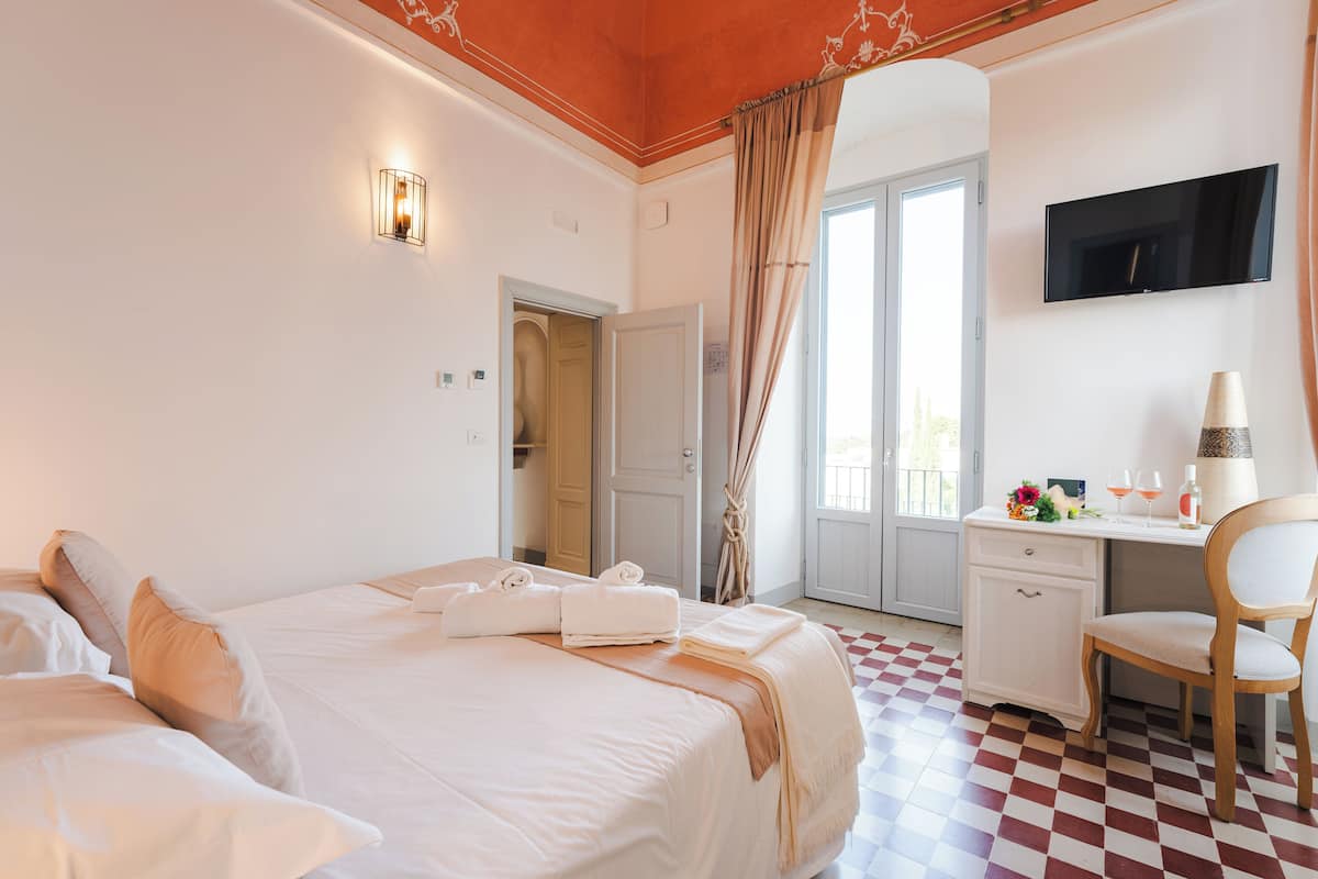 A hotel room with two beds, a desk, a chair, a TV, and a checkered floor.
