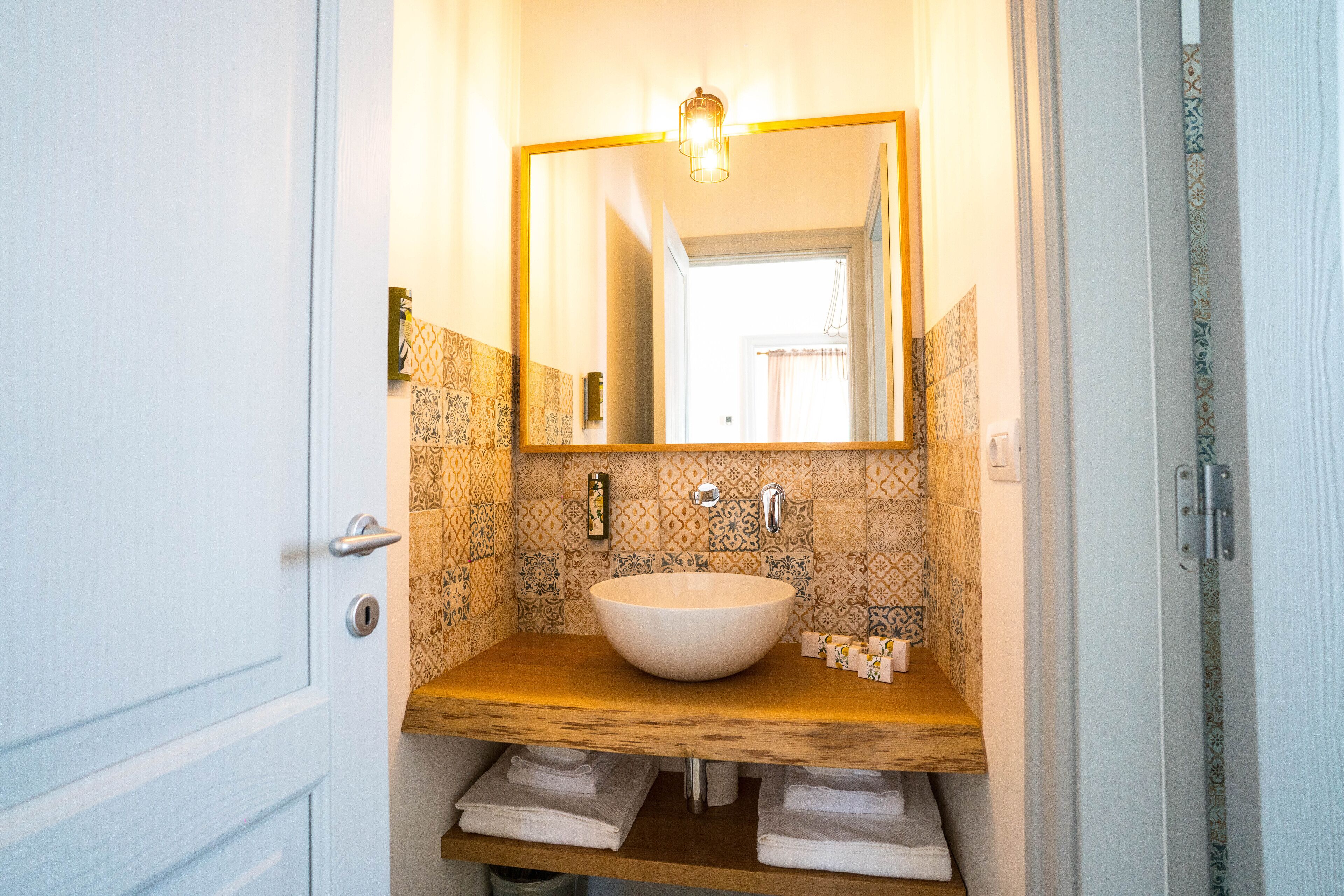 A bathroom with a wooden vanity, a white sink, and a large mirror.