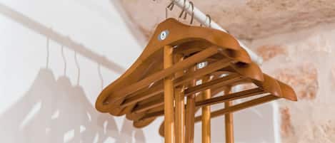 Ein Kleiderständer aus Holz mit mehreren Kleiderbügeln vor einer strukturierten Wand.