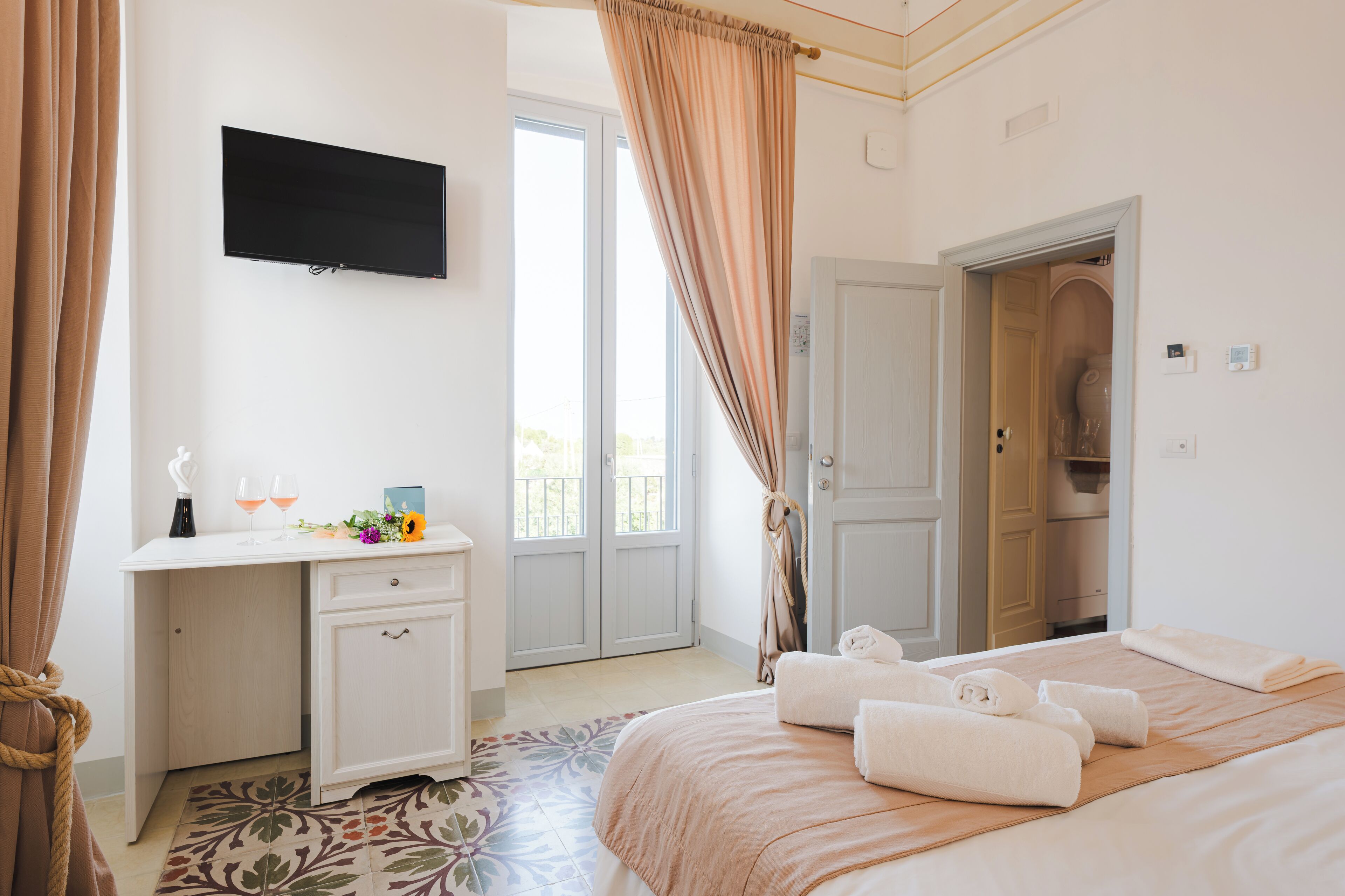 Habitación de hotel con cama, escritorio, televisor y puerta de baño.