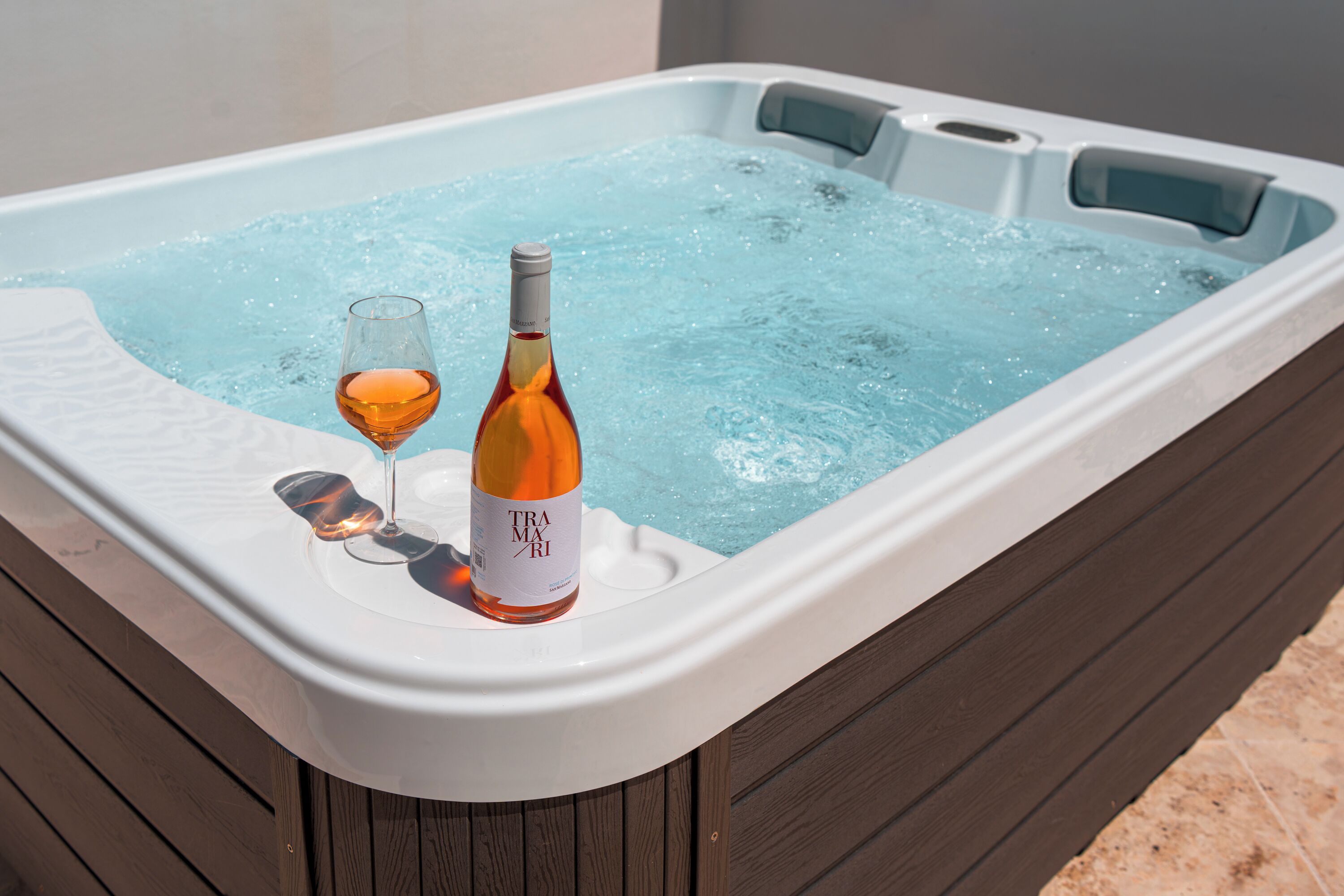 A hot tub with a bottle of wine and a glass.