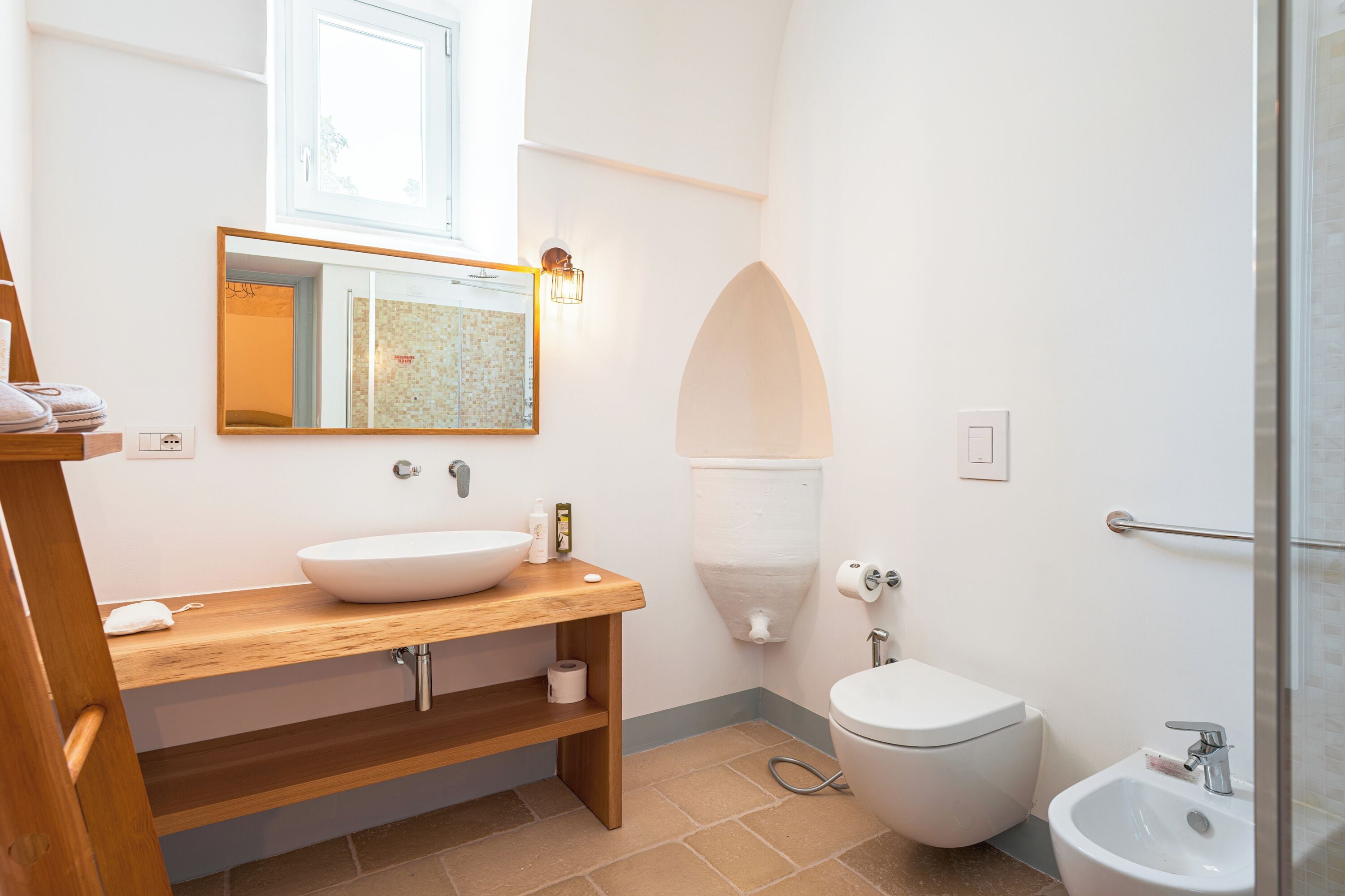 Une salle de bain avec un meuble-lavabo en bois, un lavabo blanc, des toilettes et un bidet.