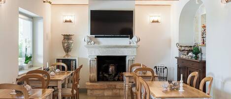 A dining area with a fireplace, a television mounted above it, and a dining table with chairs.