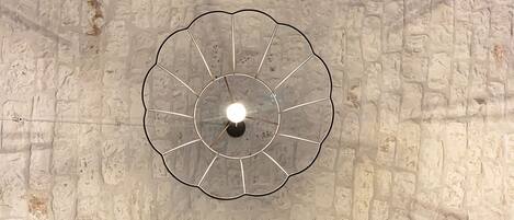 A ceiling with a circular light fixture and a textured stone wall.