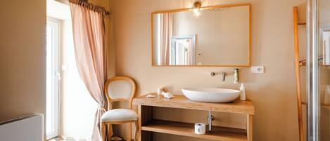 A bathroom with a wooden vanity, a large mirror, and a patterned floor.