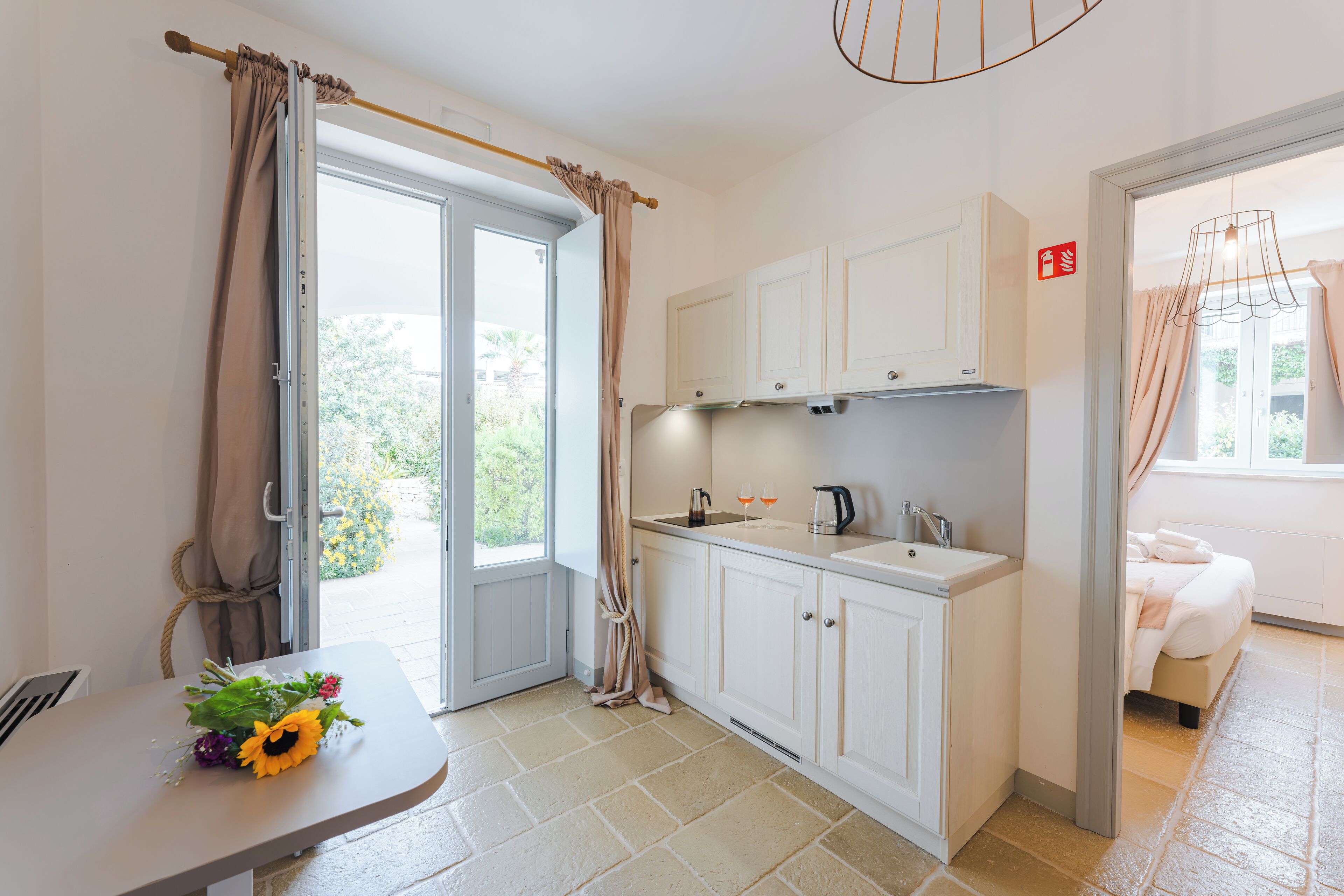 Eine moderne Küche mit weißen Schränken, einem Spülbecken und einem Essbereich mit Tisch und Blumen.