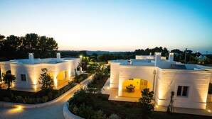 Una villa moderna con camino de entrada pavimentado, zona de estar exterior y jardín ajardinado.