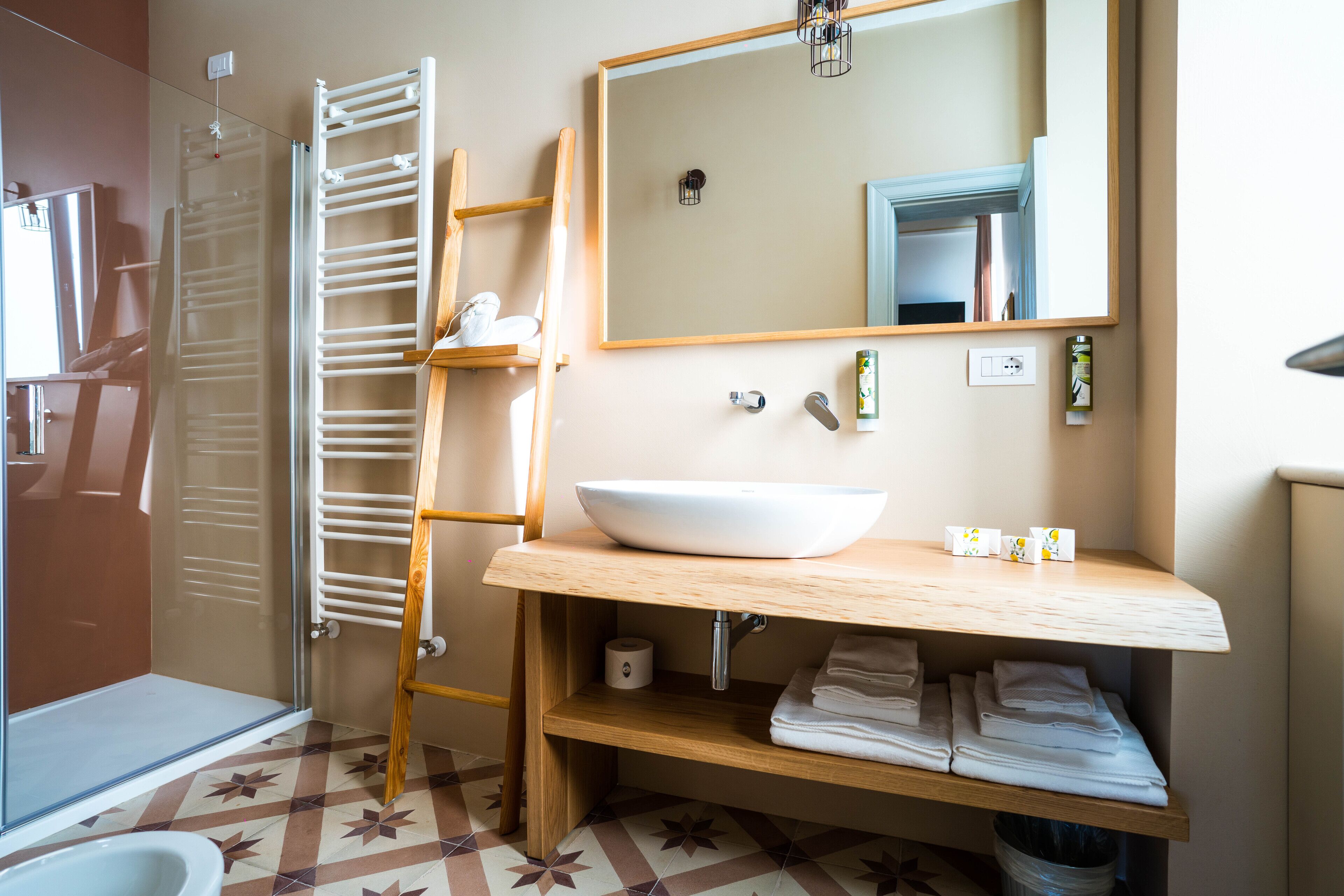 A bathroom with a wooden vanity, a large mirror, a white sink, and a towel rack.