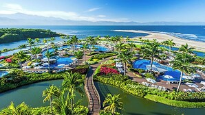 A resort with multiple swimming pools, palm trees, and a beach view.