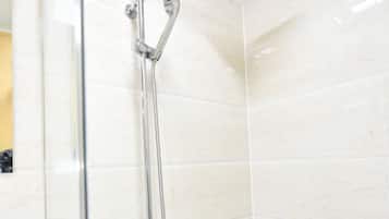 A modern bathroom with a glass-enclosed shower, a white vanity with a shelf, and tiled walls.