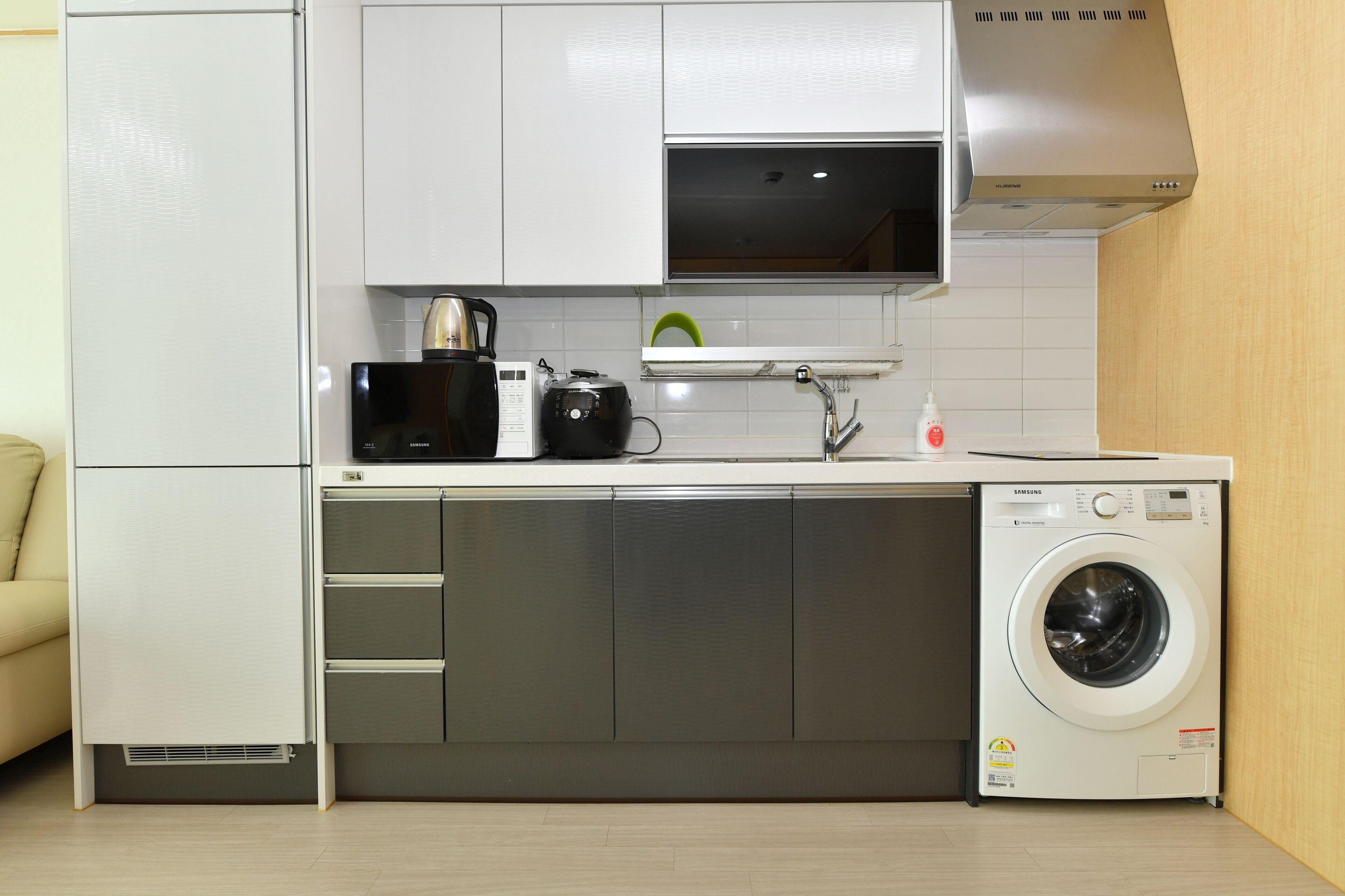 A compact kitchen with a built-in washer and dryer, a microwave, and a kettle.
