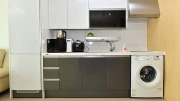 A compact kitchen with a built-in washer and dryer, a microwave, and a kettle.