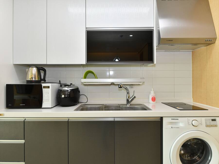 Cocina compacta con microondas, hervidor y lavadora integrada.