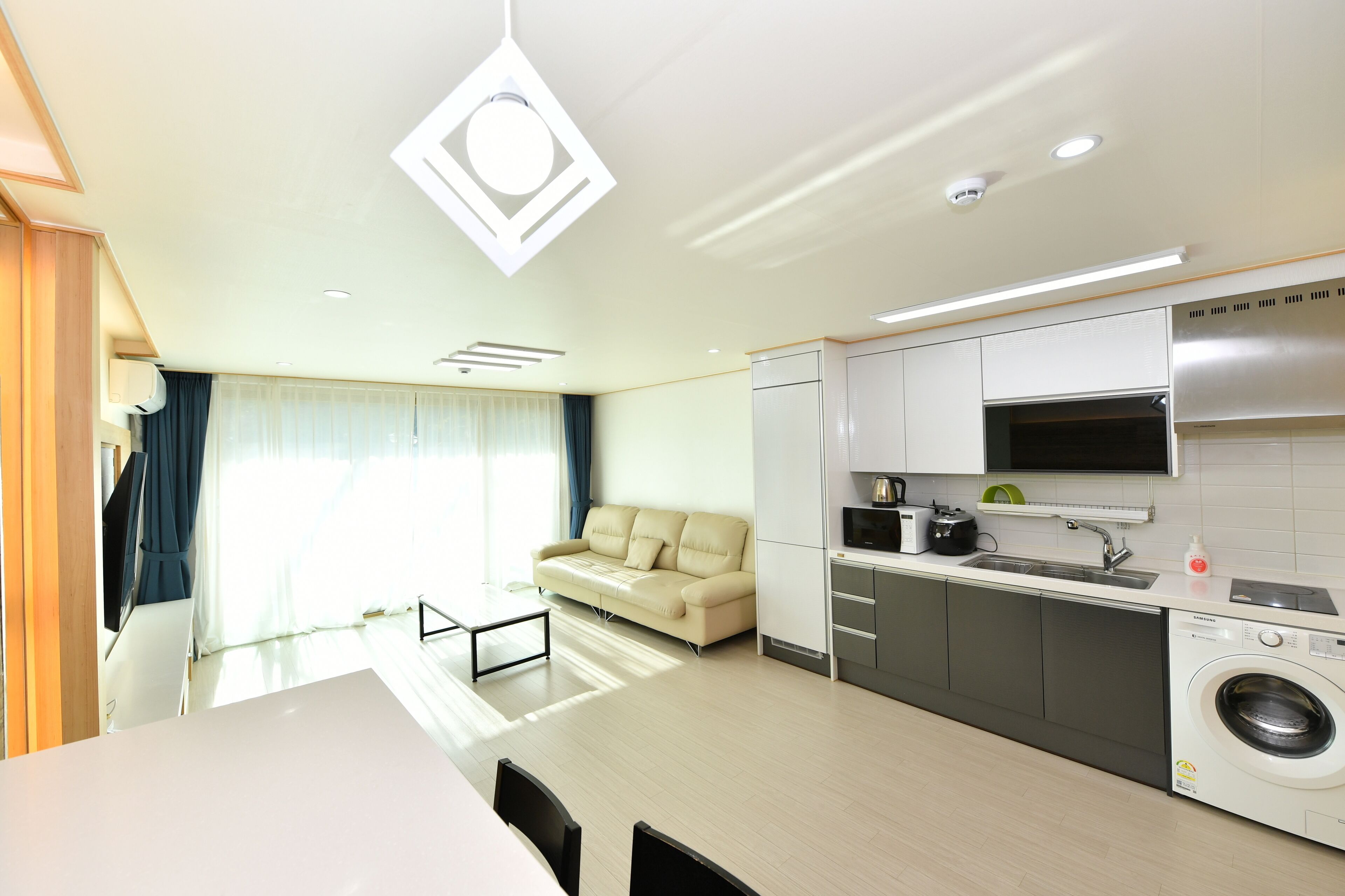 Een moderne keuken met een wasmachine, een bank en een eethoek met een tafel en stoelen.