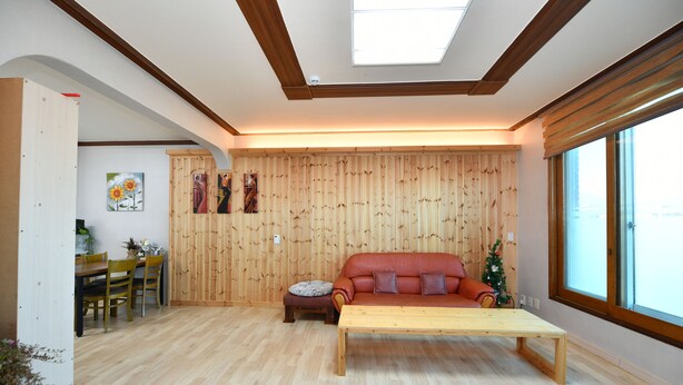 Una sala de estar moderna con piso de madera, un sofá, una mesa de centro y un comedor con sillas y una mesa.